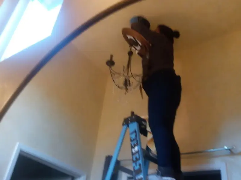 Electrician installing a chandelier in a Forsyth residence